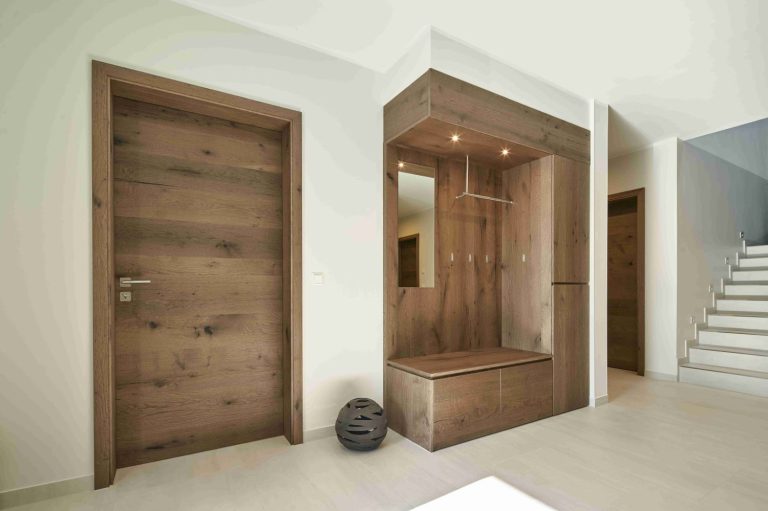 Ein moderner Eingangsbereich mit Holzdetails und einer Treppe im Hintergrund.