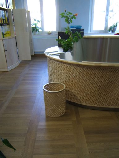 Ein Empfangstresen mit einem Müllbehälter und Pflanzen in einem hellen Raum.