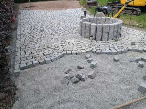 Pflastersteine sind angeordnet, mit einem Brunnen in der Mitte und unvollständigem Bereich.