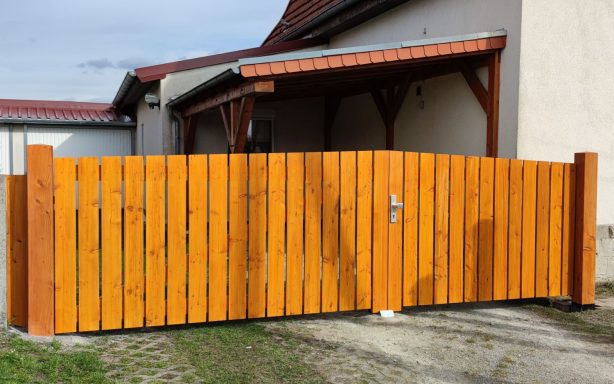 Holzzaun in warmem Farbton, um einen Zugang zu einem Gebäude herum.