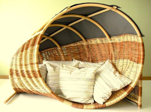 Sitzgelegenheit aus Rattan mit einer gebogenen Form und Kissen im Inneren.