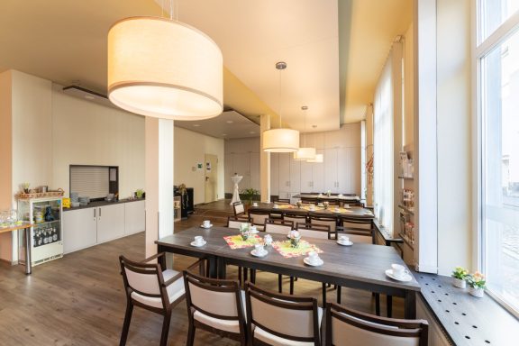 Helle, moderne Esszimmer mit großen Fenstern und einem langen Tisch in der Mitte.