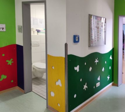 Bunte Wände in einem Flur mit Zugang zu einer Toilettentür.