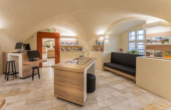 Moderne Empfangsarea mit hellen Wänden, Holztheke und bequemen Sitzgelegenheiten.