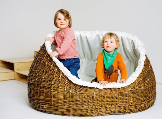 Zwei kleine Kinder sitzen in einem großen, geflochtenen Korb.