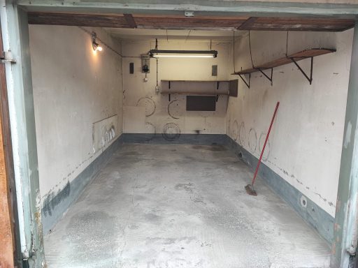 Leerer Garagenraum mit grauem Boden und einfachen Wänden, ohne Möbel oder Zugänge.