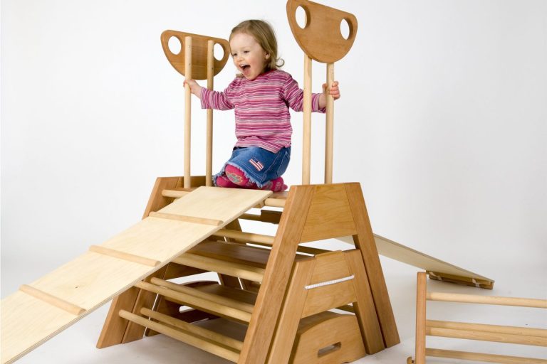 Ein Kind, das fröhlich von einer Holzspielstruktur rutscht.