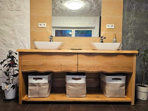 Zweifacher Waschbeckenunterschrank aus Holz mit Aufbewahrungsboxen und Pflanze.