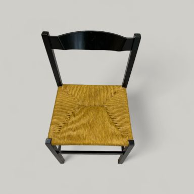 Schwarzer Holzstuhl mit geflochtener, gelber Sitzfläche.