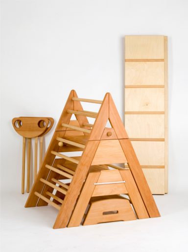 Holzspielzeug in Form einer Pyramide mit Treppen und einem Regal im Hintergrund.
