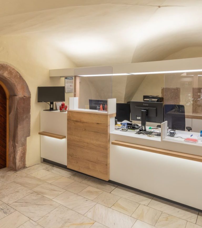 Moderne Empfangstheke mit Computern und hellen Wänden in einem Büro.