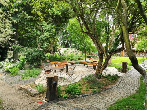 Ein ruhiger Garten mit Sitzbereichen, Bäumen und grüner Vegetation.