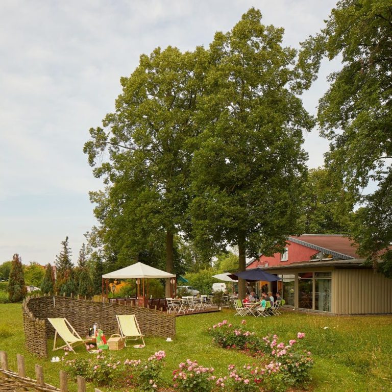 Blick auf einen Garten mit Liegen, einem Pavillon und einem Gebäude im Hintergrund.