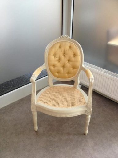 Eleganter, bequemer Stuhl mit hellbeigem Polster und verzierten Armlehnen.
