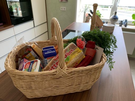 Ein Korb mit verschiedenen Lebensmitteln und frischen Kräutern.
