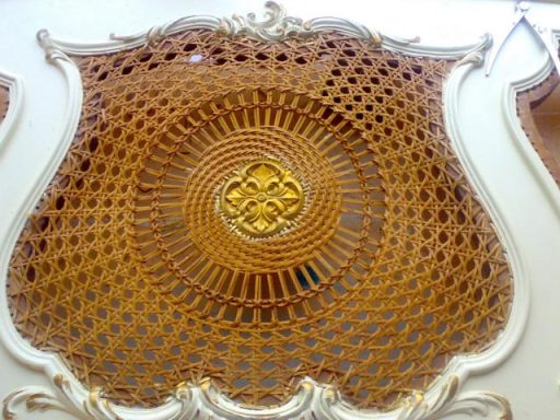 Dekorativer, runder, geflochtener Wandbelag mit goldenen Elementen.